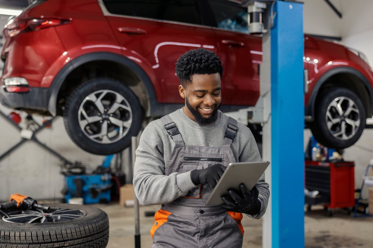 Multicultural automotive professional reviewing parts on a tablet in a service workshop